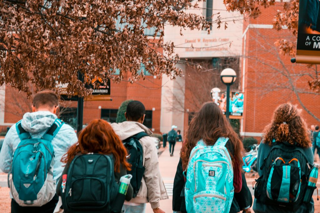 pexels-photo-1454360-1454360 A group of college students with backpacks walking together outdoors on campus.